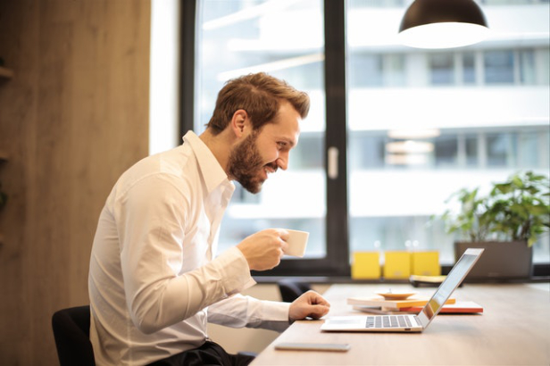 Mann sitz Kaffeetrinkend am Laptop