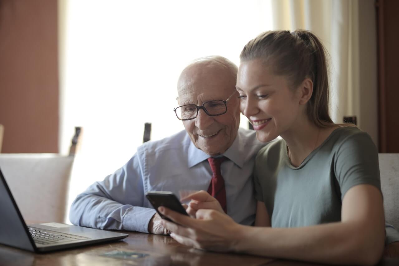 Junge Frau erklärt älterem Mann das Smartphone