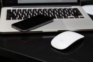 graues iphone liegt auf laptop mit einer mouse davor